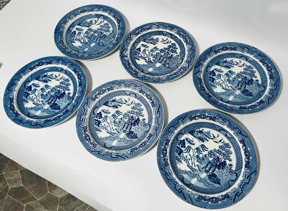 A set of six circular earthenware plates decorated with classic cobalt blue and white Willow Pattern transferware illustrations. View III