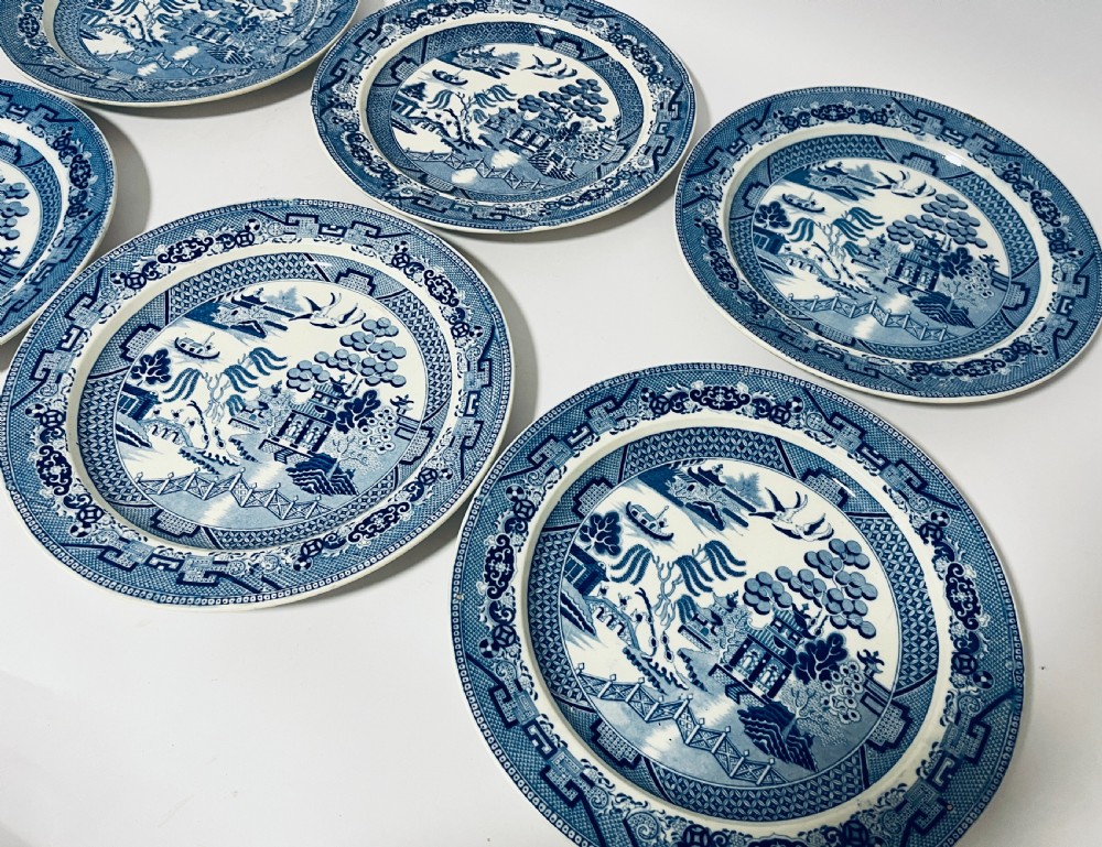 A set of six circular earthenware plates decorated with classic cobalt blue and white Willow Pattern transferware illustrations. View IV