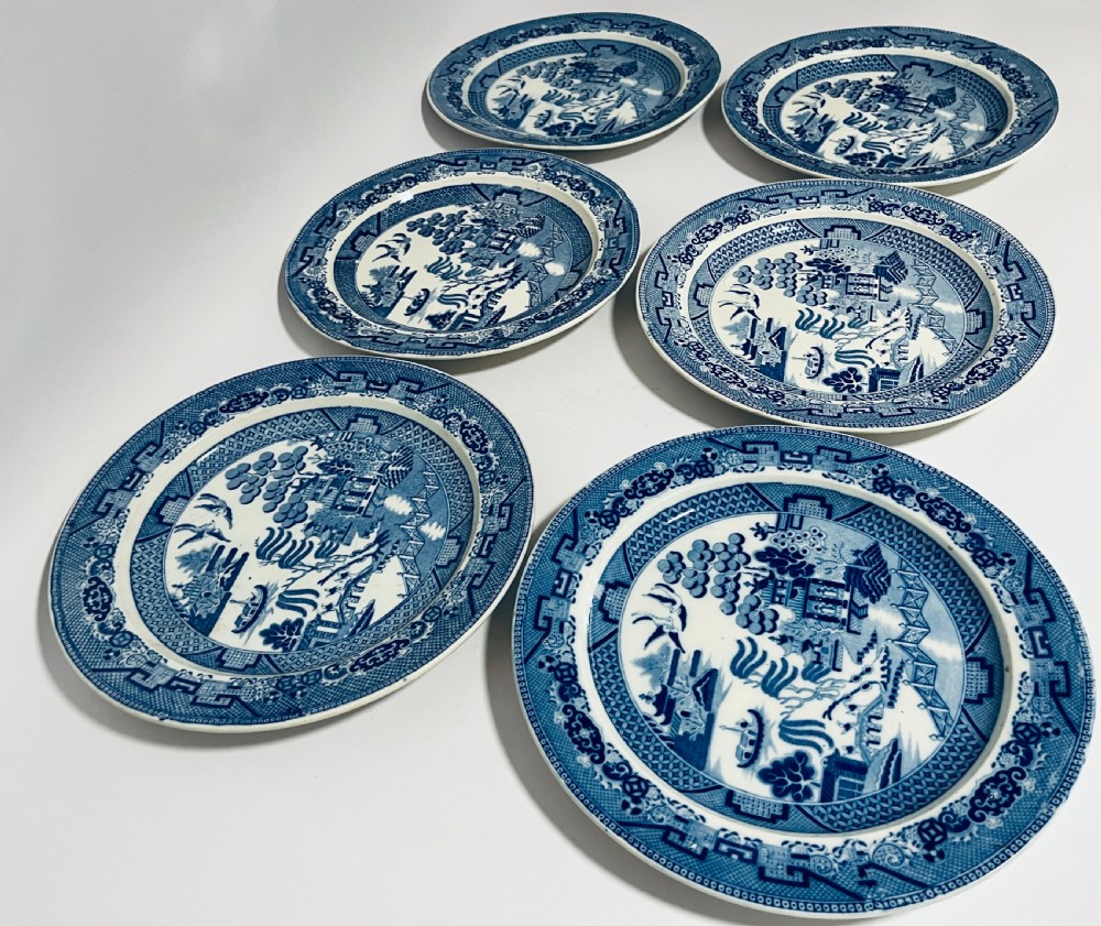 A set of six circular earthenware plates decorated with classic cobalt blue and white Willow Pattern transferware illustrations. View VIII