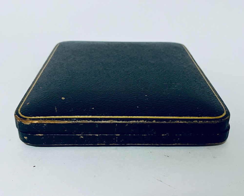 A set of six Victorian silver-handled butter knives with chased foliate handles, resting inside an open dark blue silk-lined presentation box. View IX