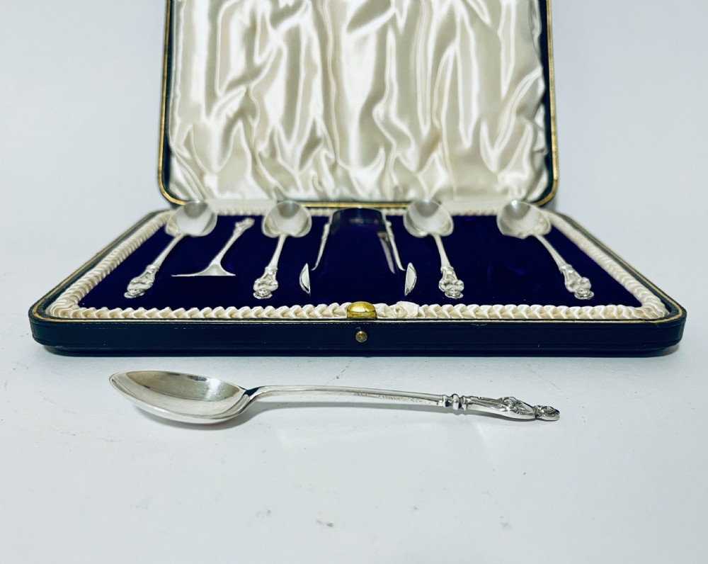 A cased set of six silver teaspoons and matching sugar tongs arranged in a blue velvet lined presentation box with cream satin lid. View V