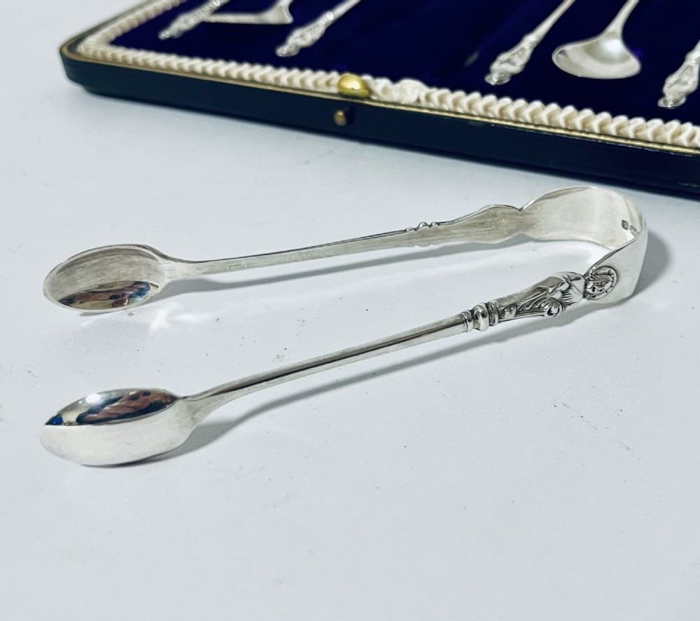 A cased set of six silver teaspoons and matching sugar tongs arranged in a blue velvet lined presentation box with cream satin lid. View X