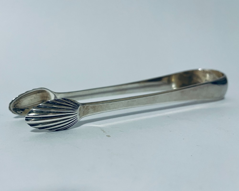 A pair of Georgian sterling silver sugar tongs featuring shell-shaped grips and smooth curved arms.