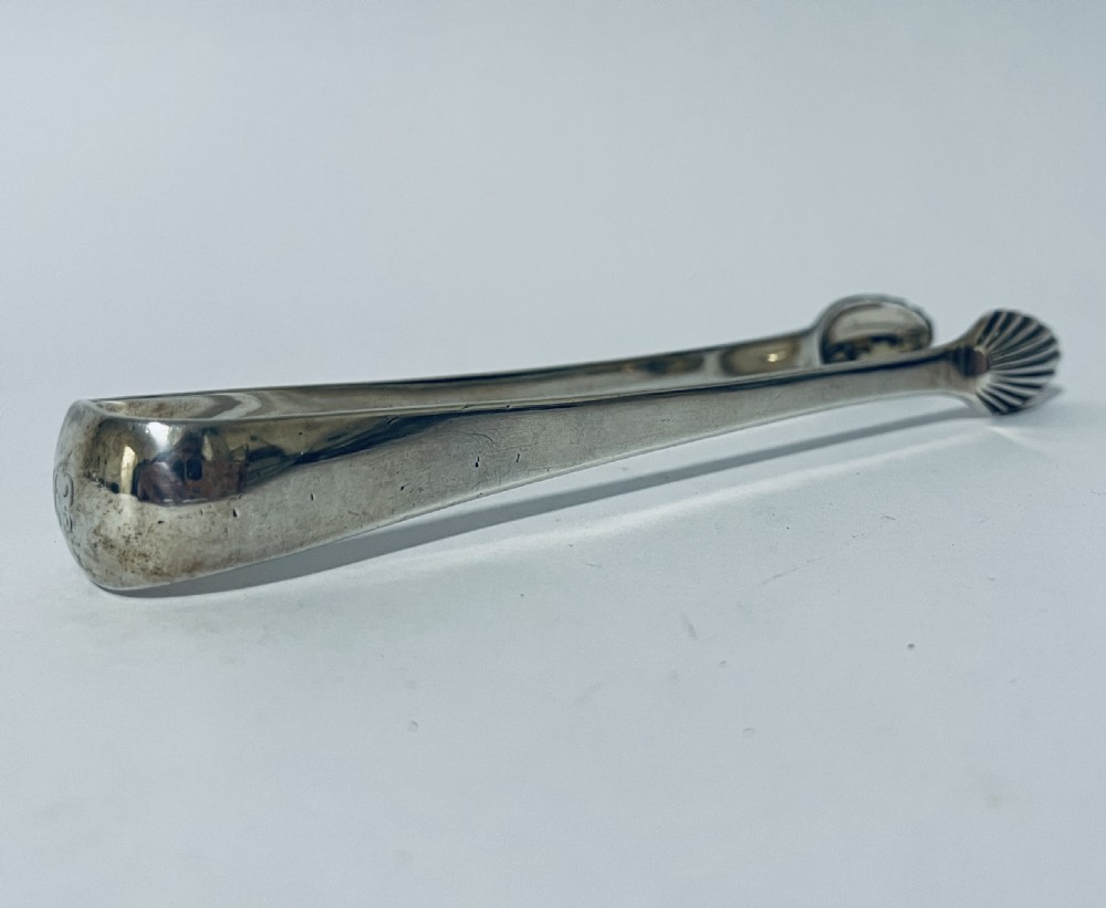 A pair of Georgian sterling silver sugar tongs featuring shell-shaped grips and smooth curved arms. View III