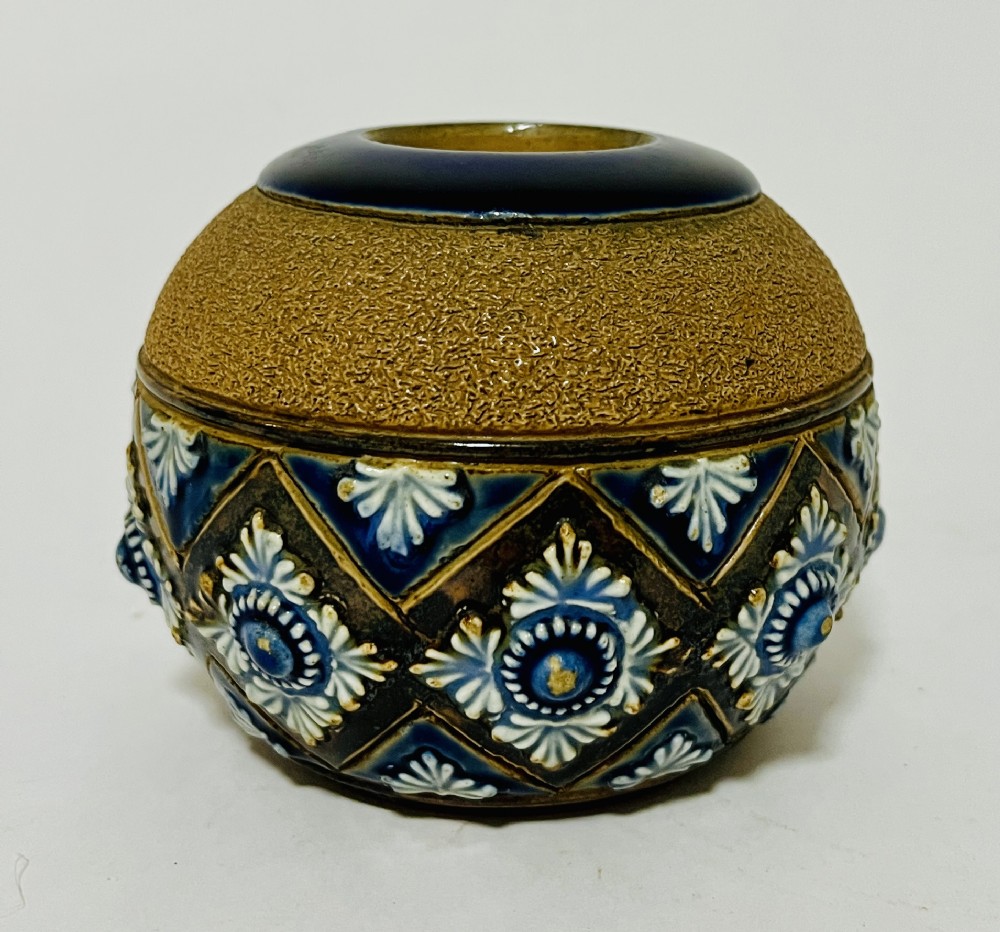 A spherical Doulton Lambeth stoneware match striker featuring a textured upper striking band and a cobalt blue diamond lattice lower section with raised white rosette motifs.
