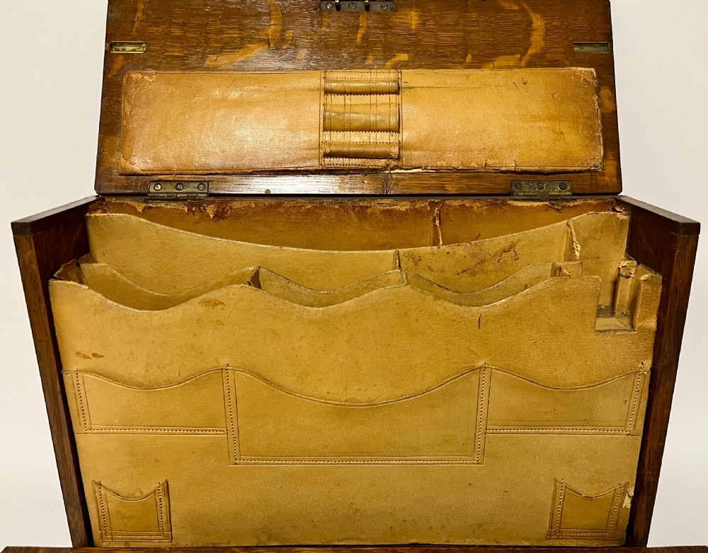 A rectangular Victorian dark oak stationery cabinet featuring a hinged drop-front, brass keyhole escutcheon, and an engraved metal plaque mounted on the top surface. View VII