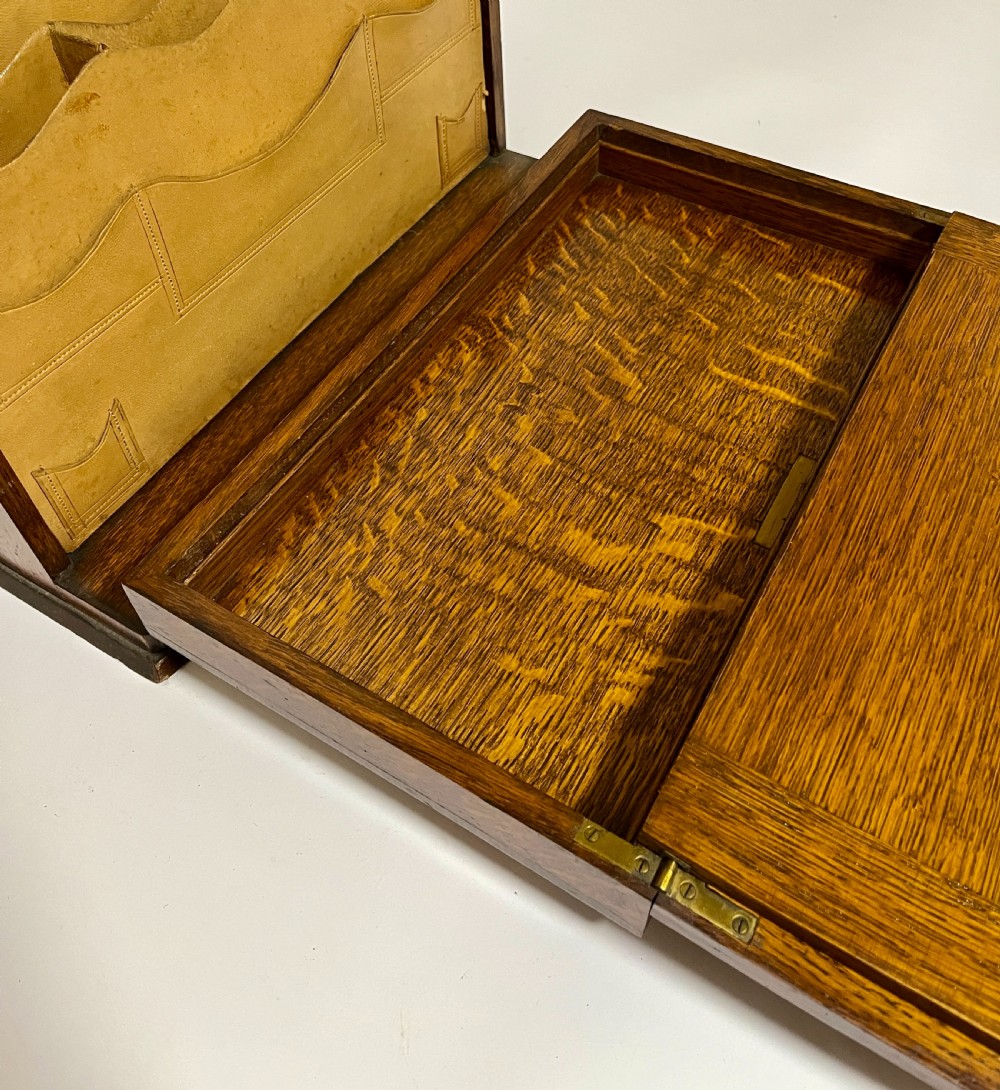 A rectangular Victorian dark oak stationery cabinet featuring a hinged drop-front, brass keyhole escutcheon, and an engraved metal plaque mounted on the top surface. View VIII