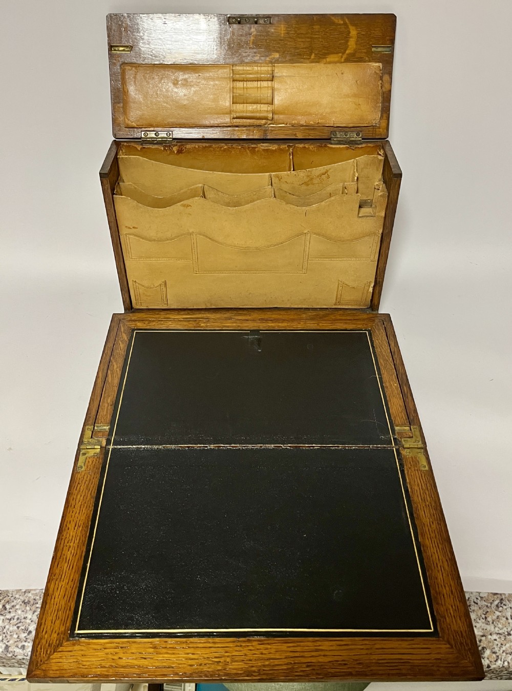 A rectangular Victorian dark oak stationery cabinet featuring a hinged drop-front, brass keyhole escutcheon, and an engraved metal plaque mounted on the top surface. View X