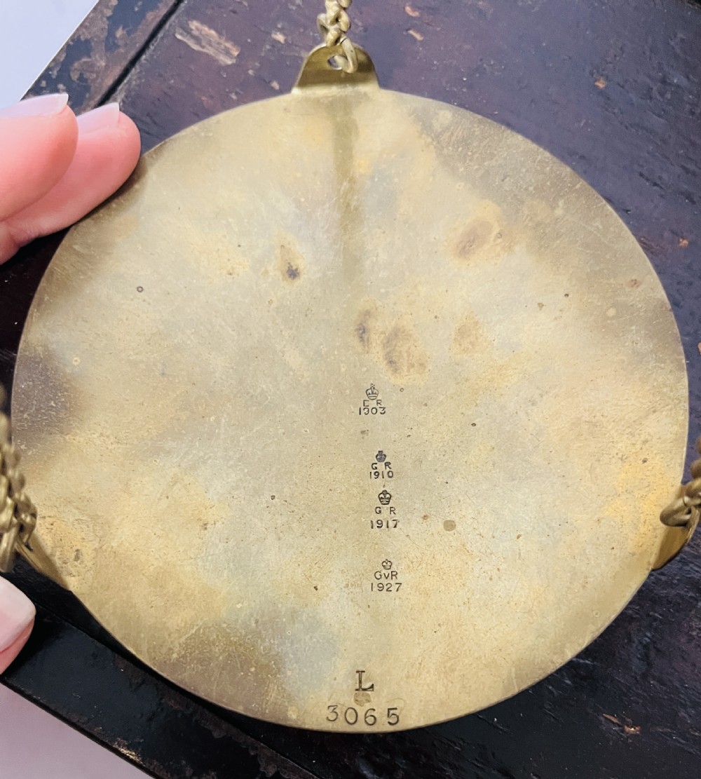 An antique brass balance scale stamped with County of Devon markings, resting on a black fitted transport case with two suspended brass pans. View XVI