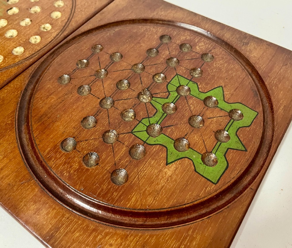 A two-panel antique mahogany solitaire games board featuring indented circular playing tracks alongside a collection of dark glass marbles. View IX