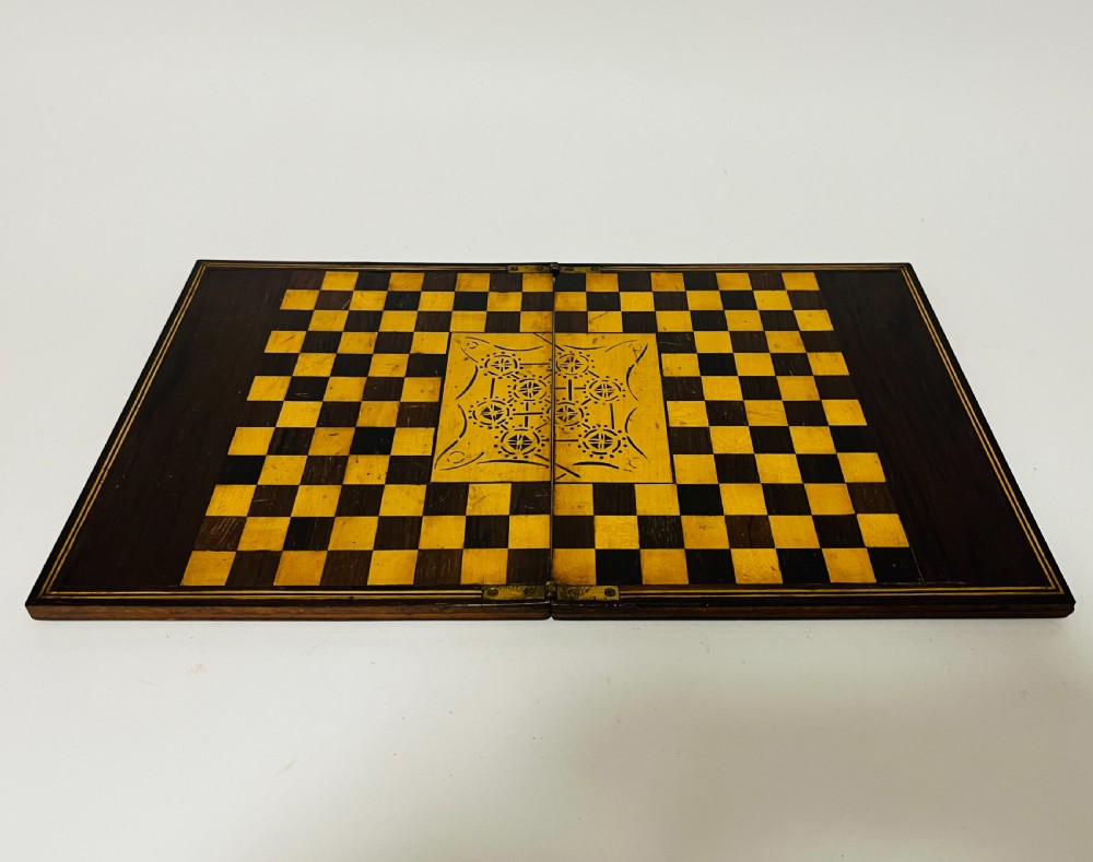 A two-panel antique mahogany solitaire games board featuring indented circular playing tracks alongside a collection of dark glass marbles. View XII