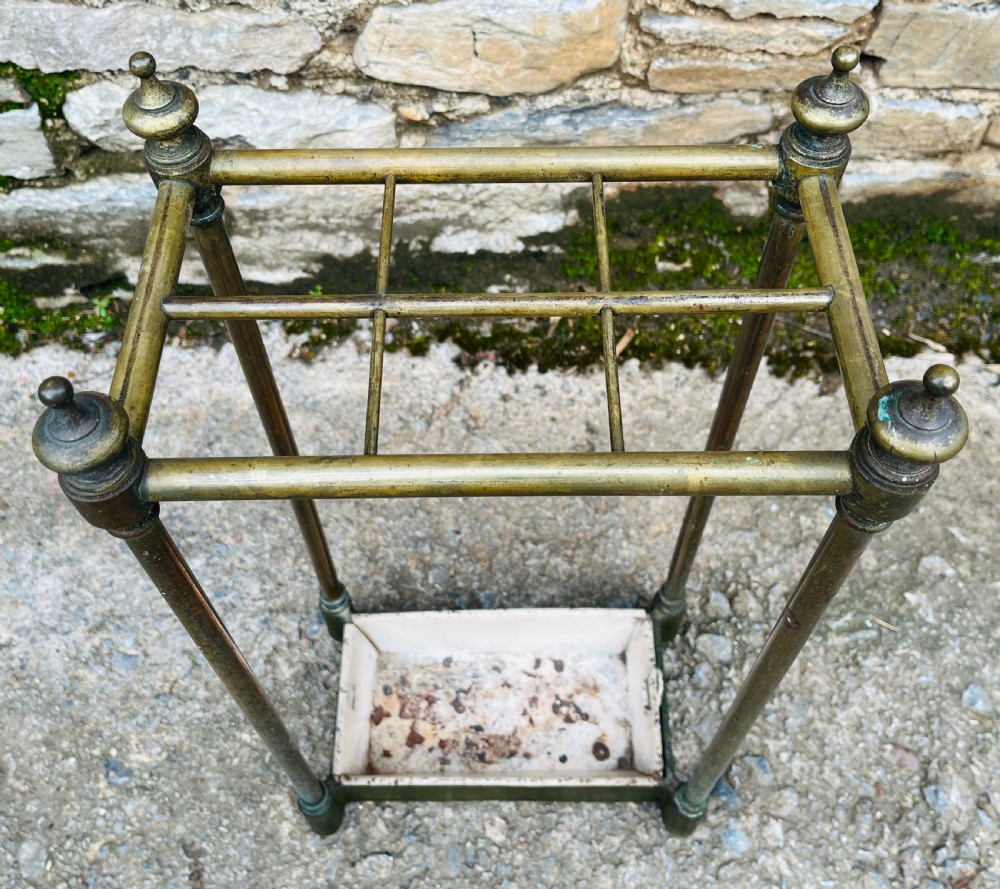 A Victorian brass stick stand featuring four upright posts with turned finials, a six-division top frame, and a painted metal drip tray at the base. View III