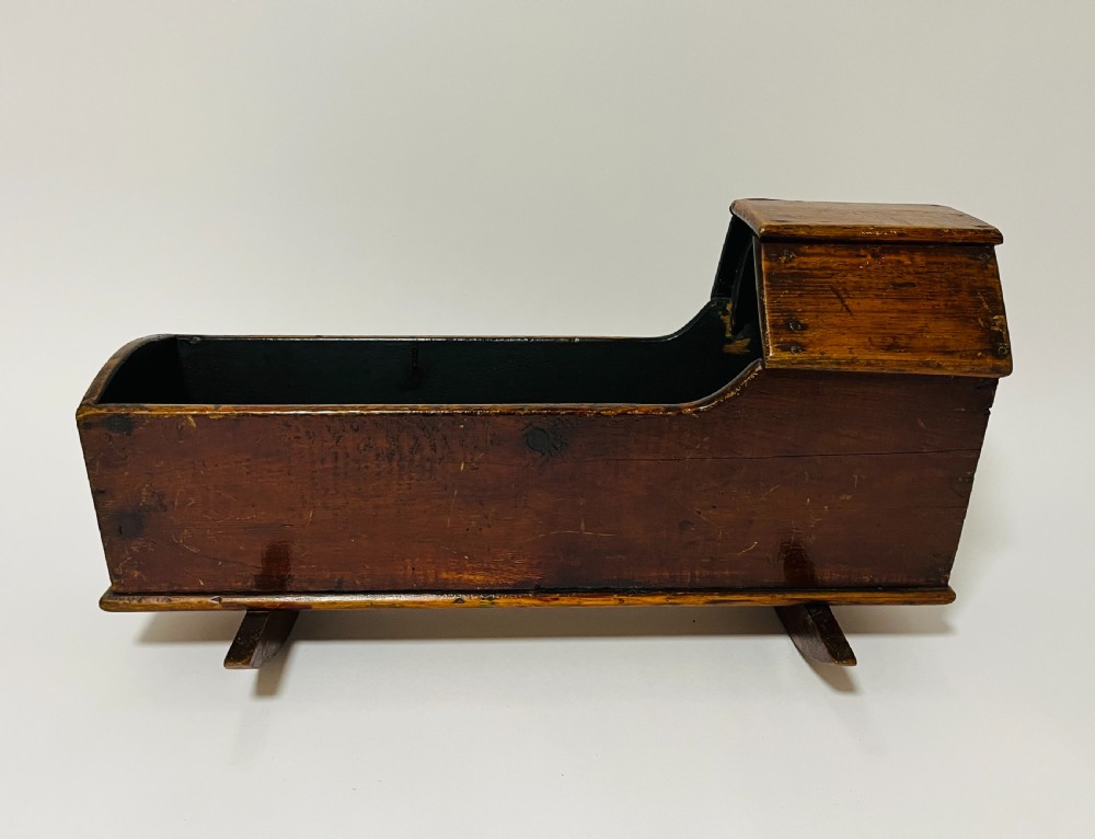 A dark stained pine miniature doll cradle featuring a hooded canopy and curved rockers. View II