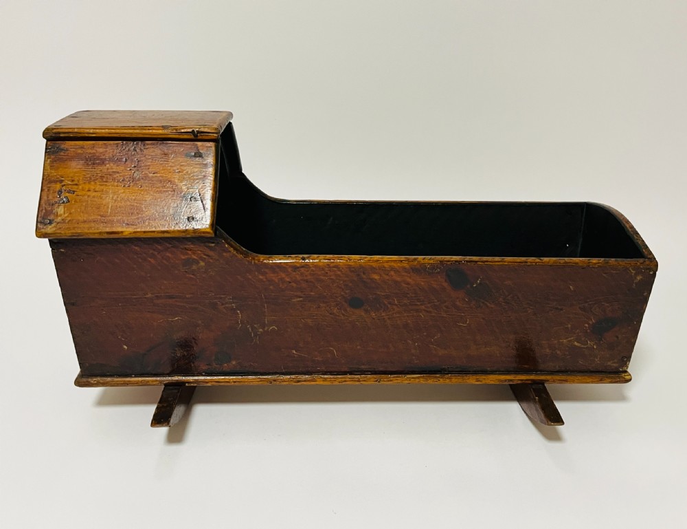 A dark stained pine miniature doll cradle featuring a hooded canopy and curved rockers. View V