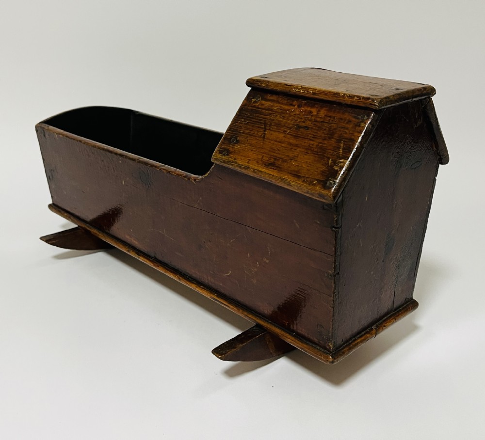 A dark stained pine miniature doll cradle featuring a hooded canopy and curved rockers. View IX