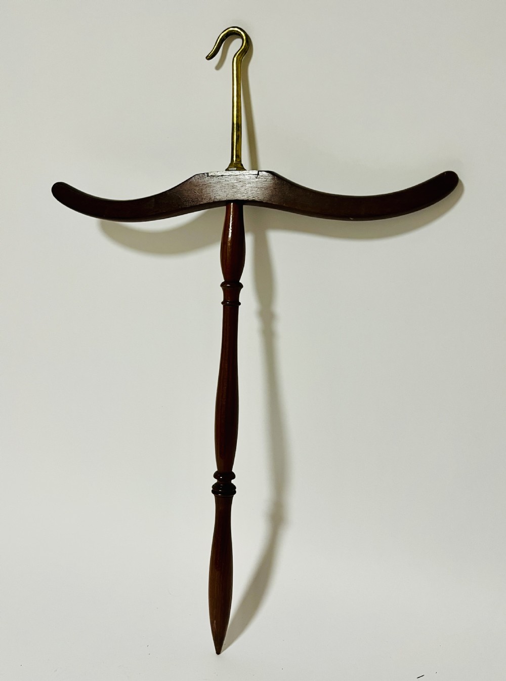 An antique dark mahogany gown and wig hanger featuring a contoured wooden shoulder bar, a turned central spindle, and a brass hook. View V