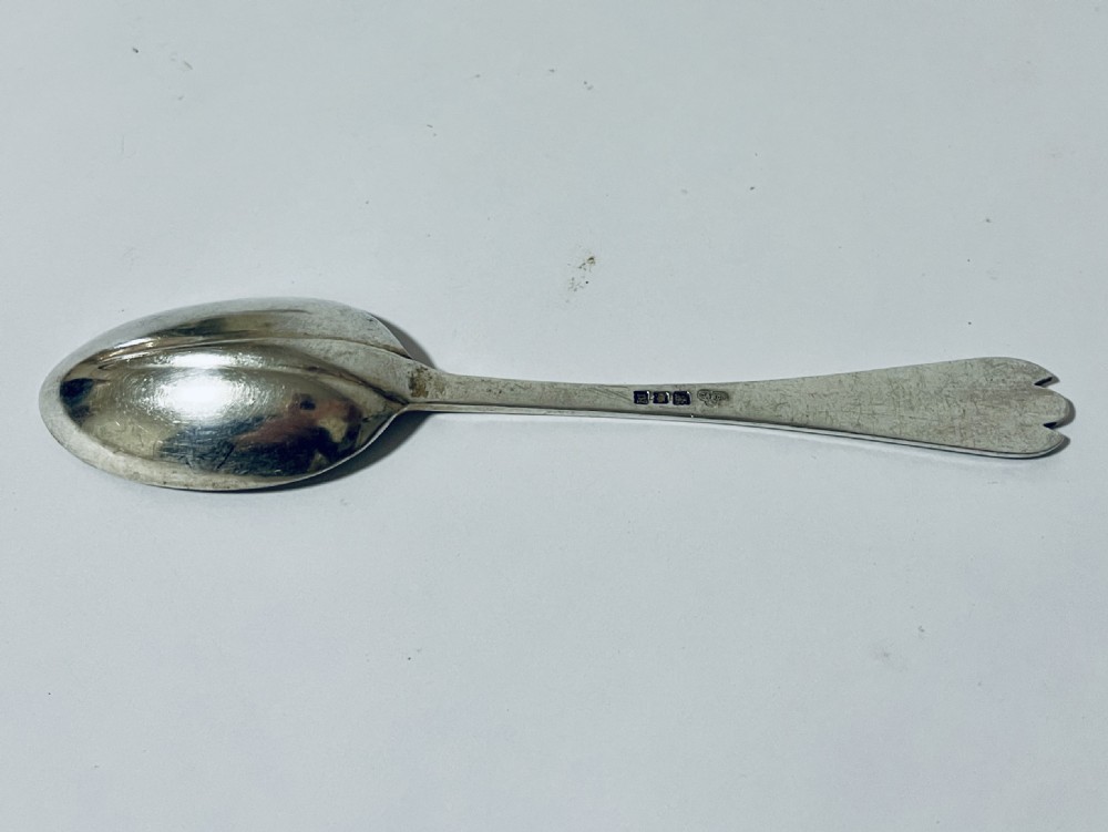 An antique silver trefid spoon featuring a shallow oval bowl and a flat stem terminating in a distinctive notched three-pointed shape. View IV