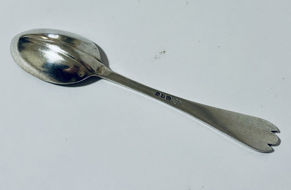 An antique silver trefid spoon featuring a shallow oval bowl and a flat stem terminating in a distinctive notched three-pointed shape. View V