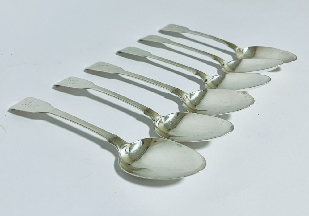 A set of six Georgian sterling silver tablespoons with oval bowls and engraved initial terminals laid out diagonally. View II