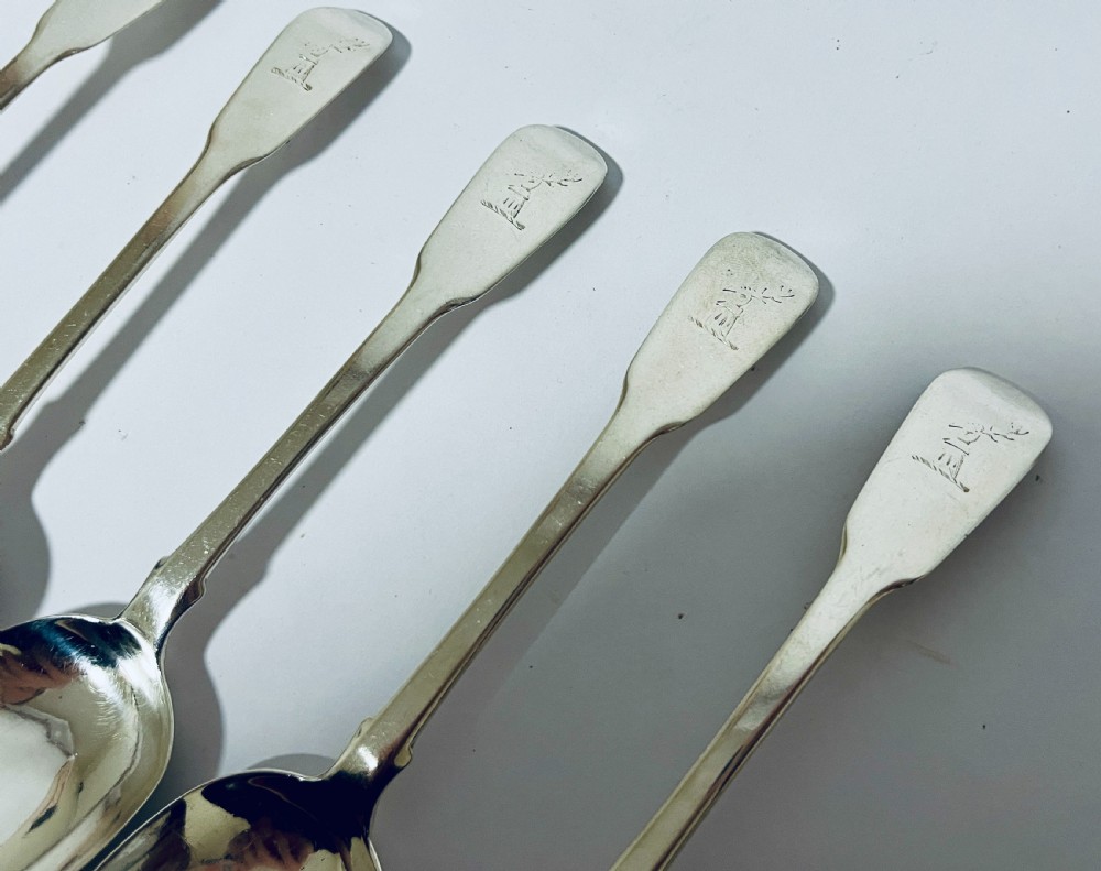 A set of six Georgian sterling silver tablespoons with oval bowls and engraved initial terminals laid out diagonally. View V