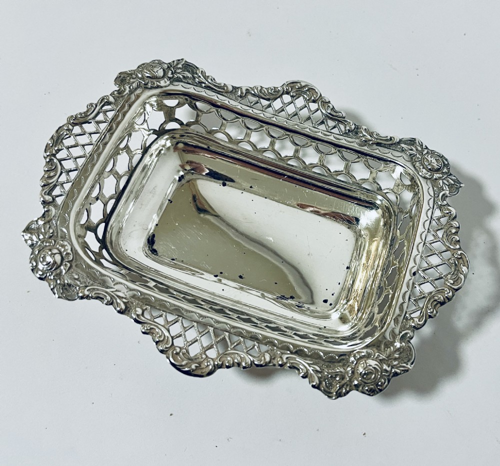 A rectangular Victorian silver bonbon dish featuring a smooth central basin surrounded by openwork pierced lattice rims and floral corner accents.