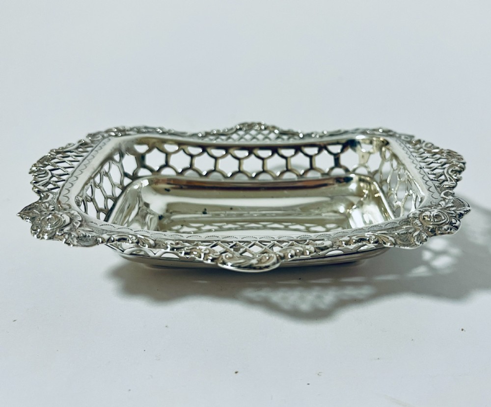 A rectangular Victorian silver bonbon dish featuring a smooth central basin surrounded by openwork pierced lattice rims and floral corner accents. View II