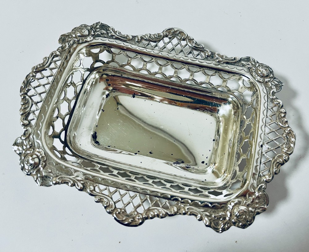 A rectangular Victorian silver bonbon dish featuring a smooth central basin surrounded by openwork pierced lattice rims and floral corner accents. View III