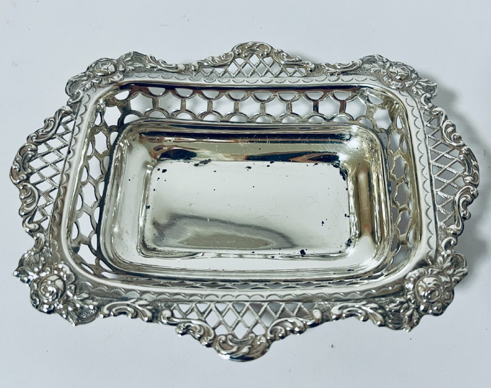 A rectangular Victorian silver bonbon dish featuring a smooth central basin surrounded by openwork pierced lattice rims and floral corner accents. View IV