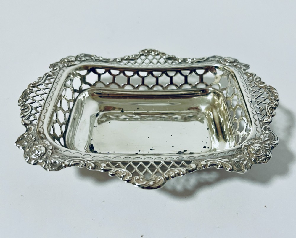 A rectangular Victorian silver bonbon dish featuring a smooth central basin surrounded by openwork pierced lattice rims and floral corner accents. View V