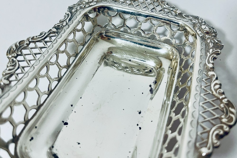 A rectangular Victorian silver bonbon dish featuring a smooth central basin surrounded by openwork pierced lattice rims and floral corner accents. View VII