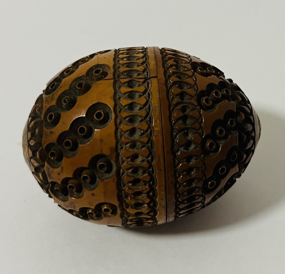 An egg-shaped Victorian pomander carved from warm brown coquilla nut with geometric circular pierced patterns.