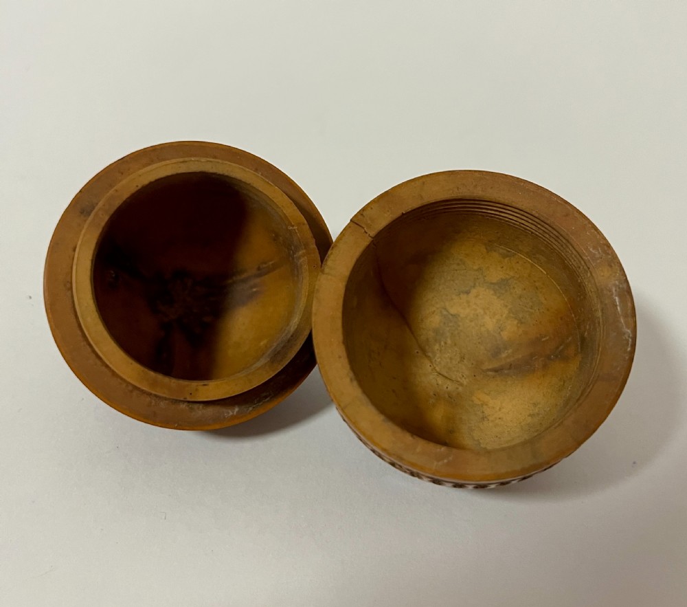 An egg-shaped Victorian pomander carved from warm brown coquilla nut with geometric circular pierced patterns. View VII
