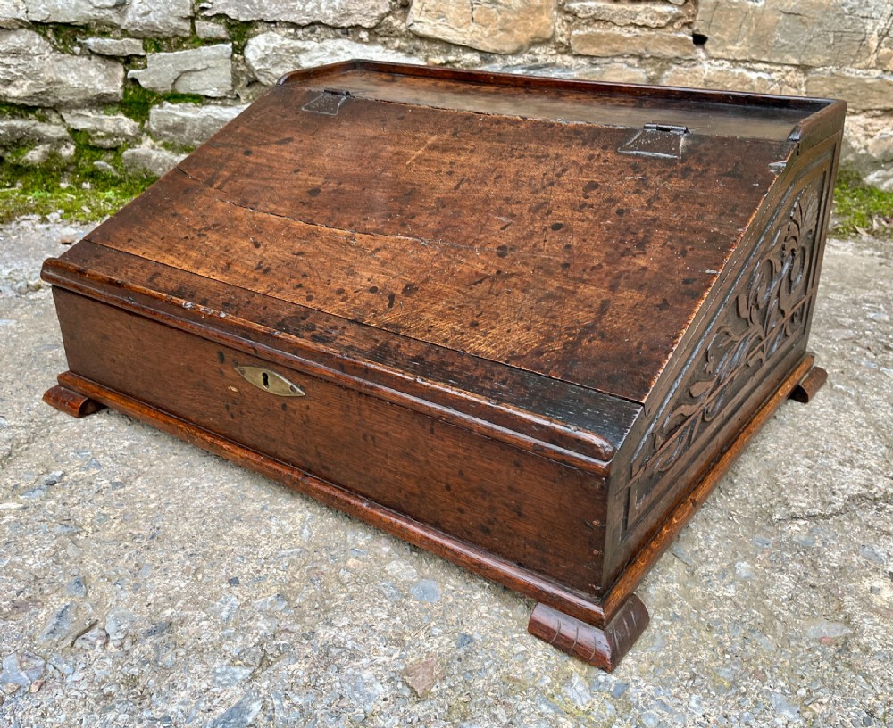 A 17th-century dark oak slant-top desk box featuring iron butterfly hinges and a central brass keyhole escutcheon. View VIII