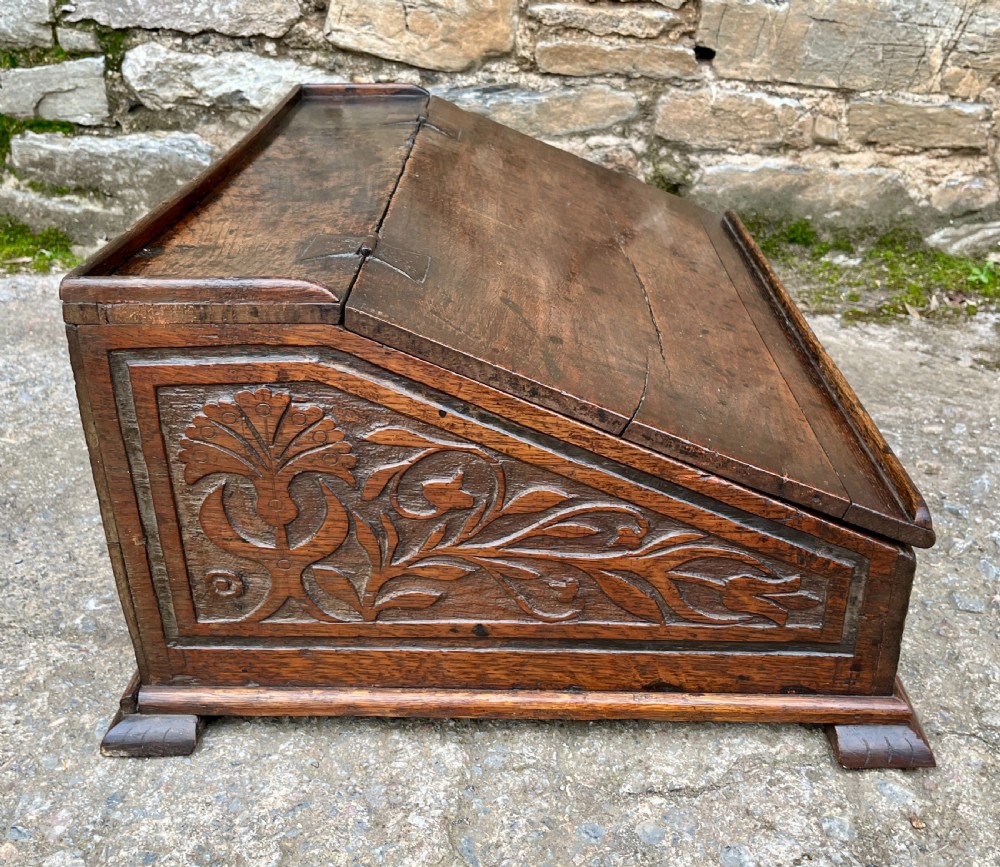 A 17th-century dark oak slant-top desk box featuring iron butterfly hinges and a central brass keyhole escutcheon. View X