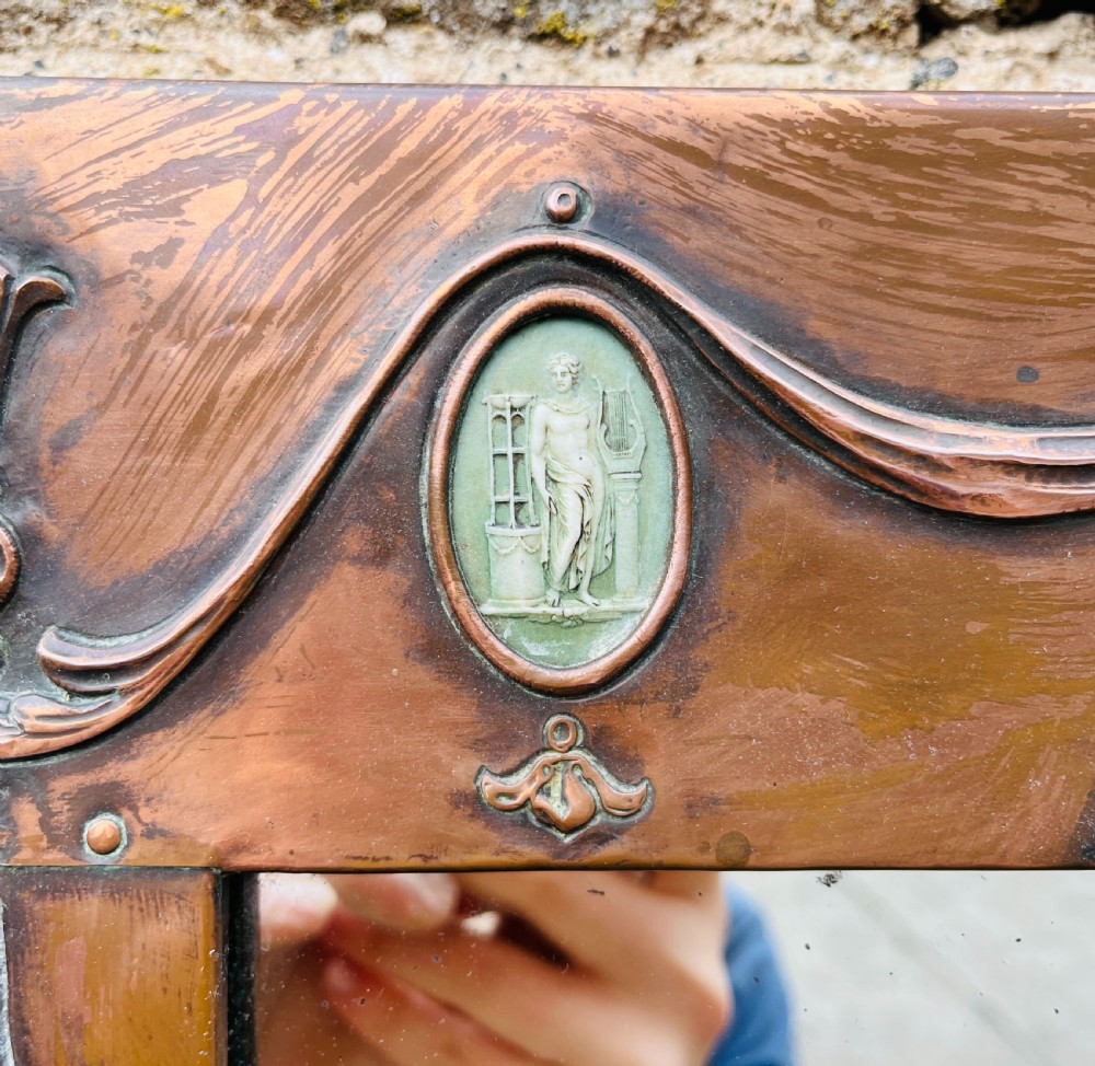 A rectangular Arts and Crafts wall mirror with an embossed copper frame featuring classical festoon motifs, an arched crest, and small green oval ceramic plaques. View III