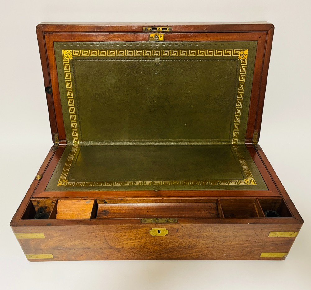 A rectangular mahogany wooden writing slope featuring protective brass corner brackets, brass straps, a central brass plaque, and a brass keyhole escutcheon. View II