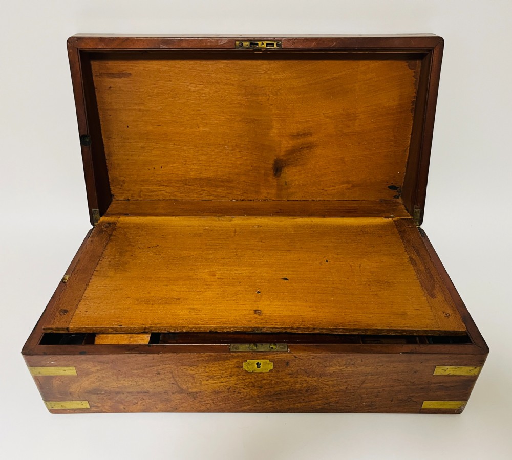 A rectangular mahogany wooden writing slope featuring protective brass corner brackets, brass straps, a central brass plaque, and a brass keyhole escutcheon. View III