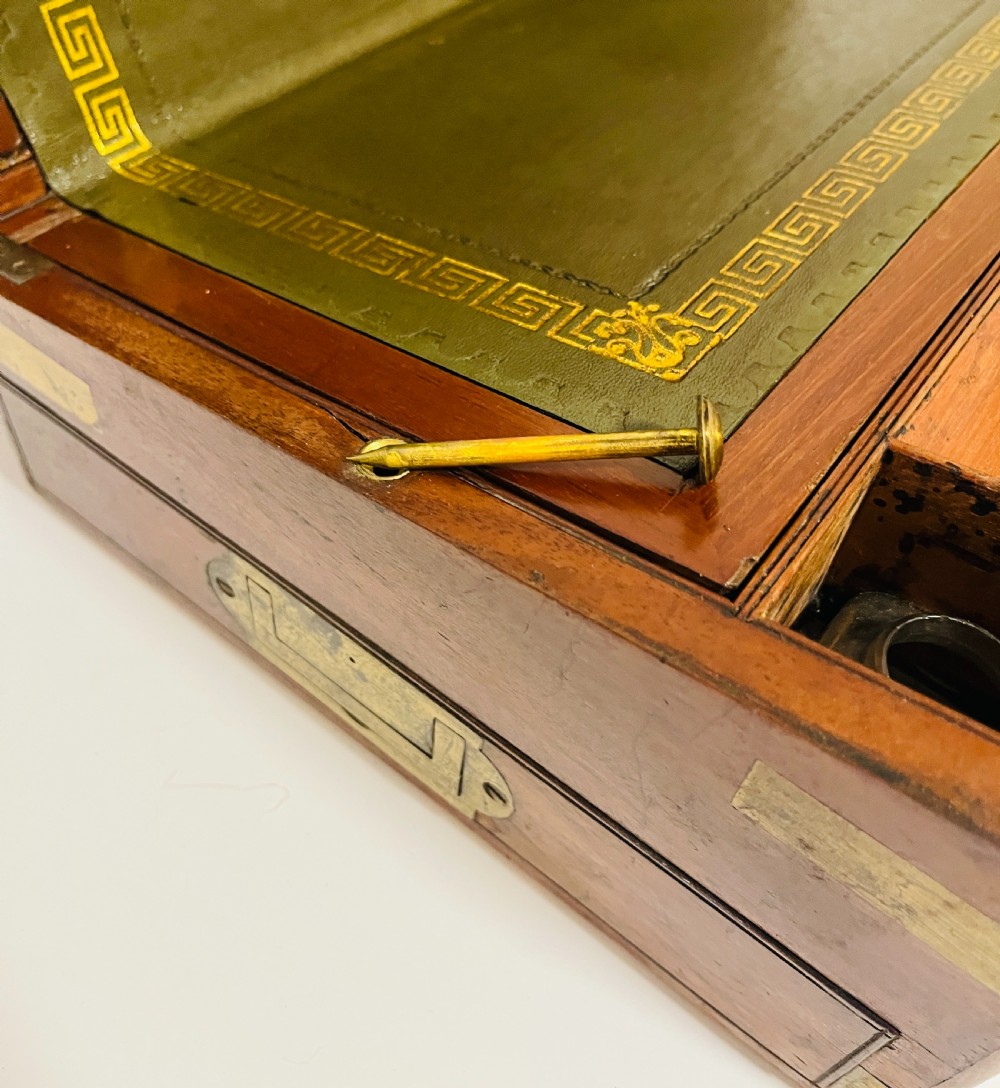 A rectangular mahogany wooden writing slope featuring protective brass corner brackets, brass straps, a central brass plaque, and a brass keyhole escutcheon. View V