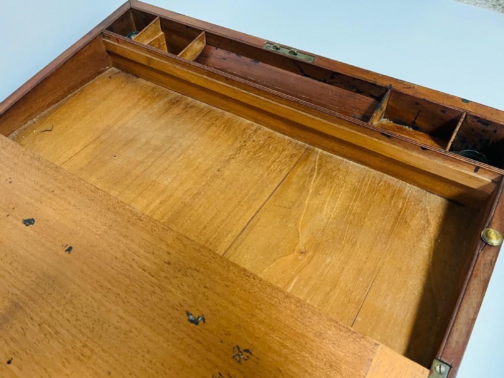 A rectangular mahogany wooden writing slope featuring protective brass corner brackets, brass straps, a central brass plaque, and a brass keyhole escutcheon. View X