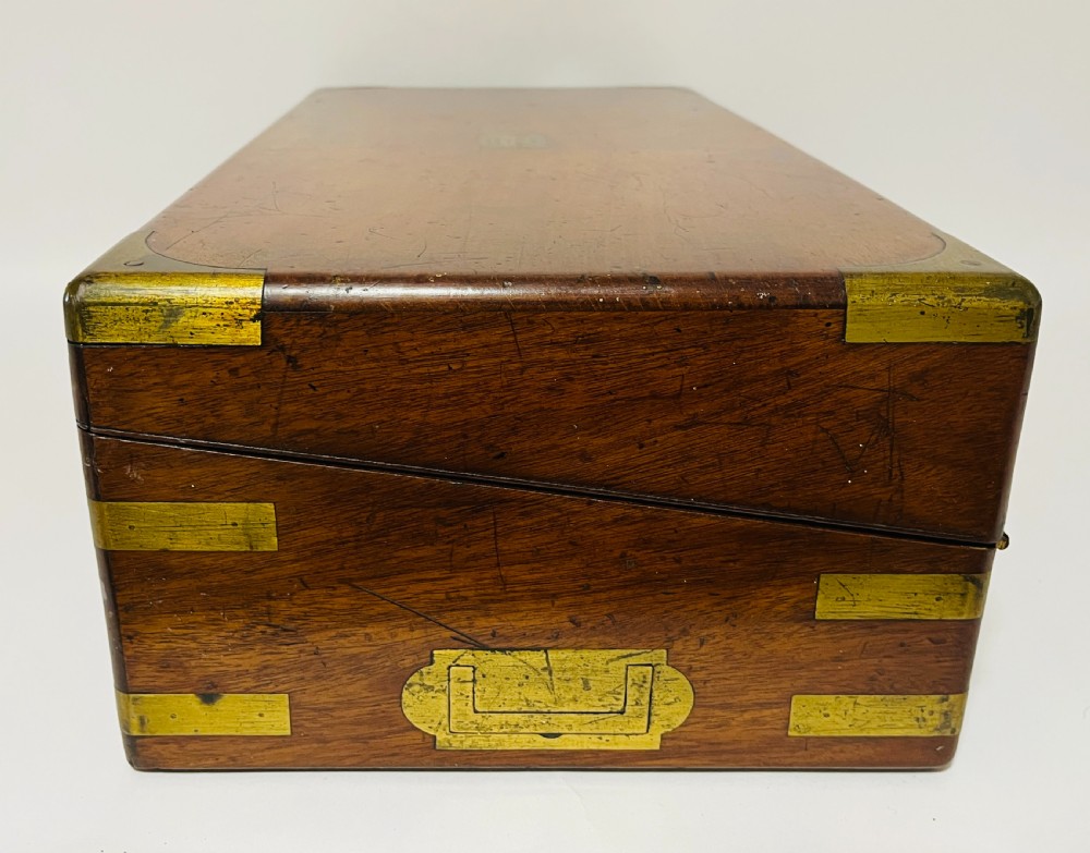 A rectangular mahogany wooden writing slope featuring protective brass corner brackets, brass straps, a central brass plaque, and a brass keyhole escutcheon. View XIII