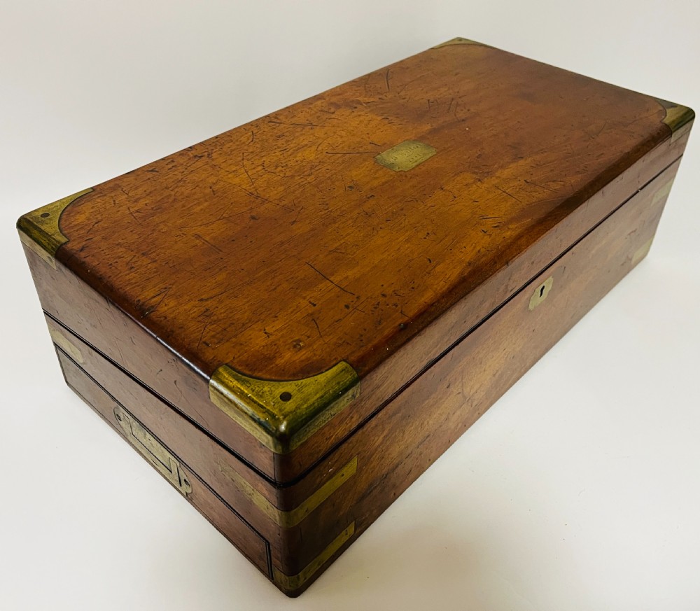 A rectangular mahogany wooden writing slope featuring protective brass corner brackets, brass straps, a central brass plaque, and a brass keyhole escutcheon. View XV