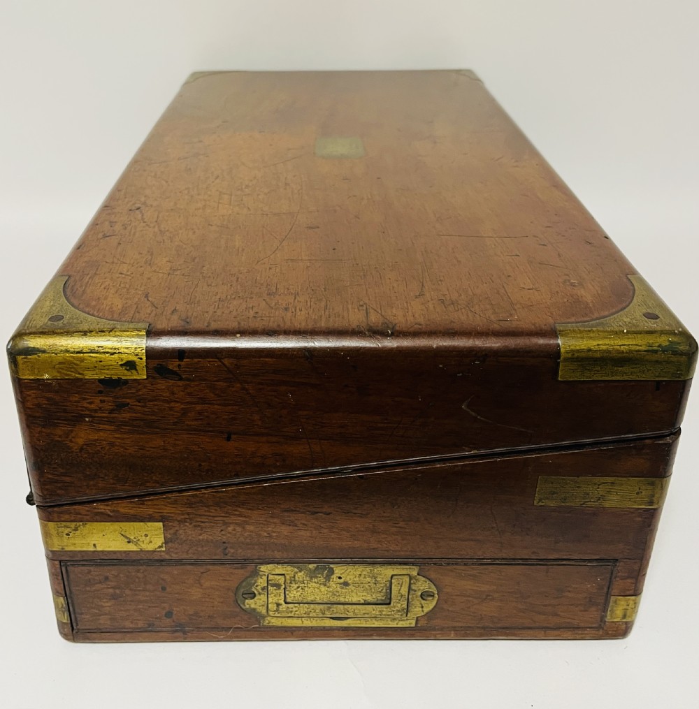 A rectangular mahogany wooden writing slope featuring protective brass corner brackets, brass straps, a central brass plaque, and a brass keyhole escutcheon. View XVII