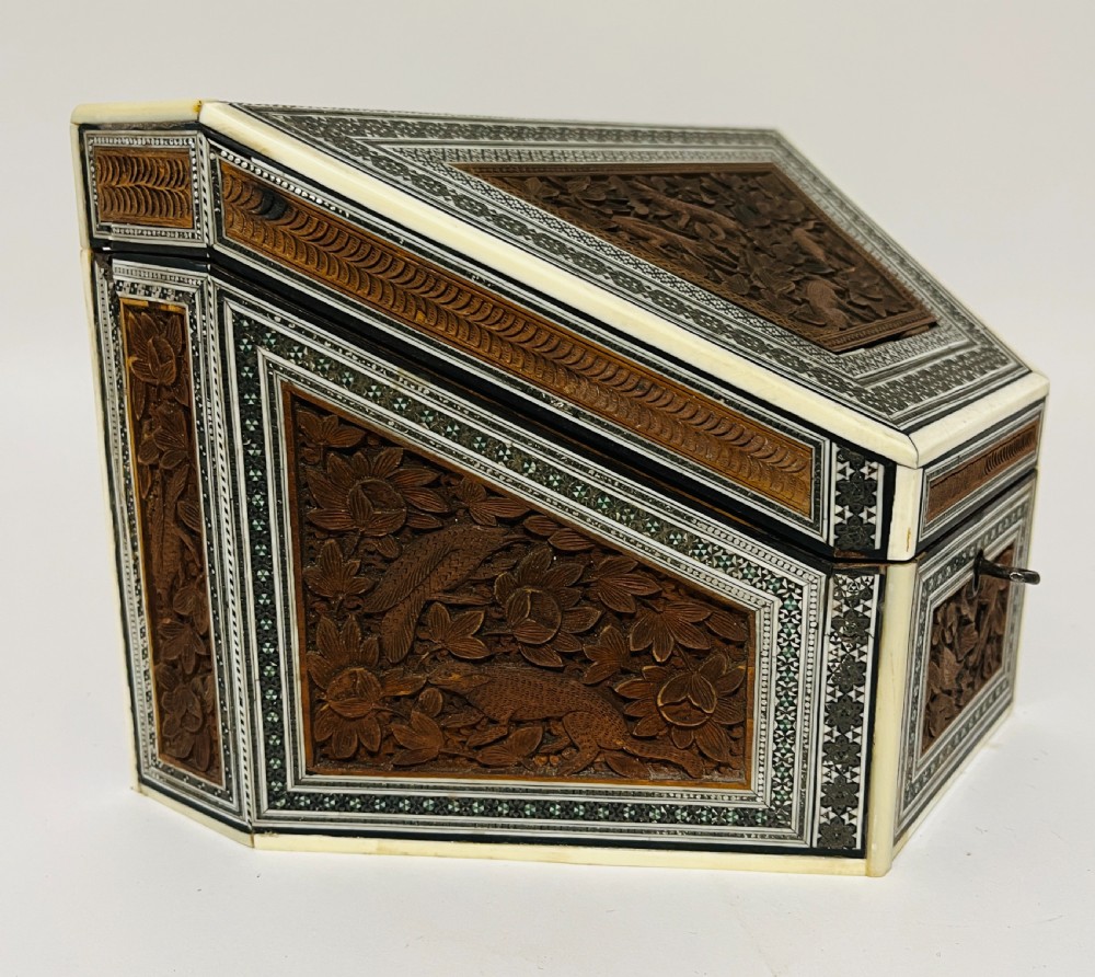 A slanted Anglo-Indian stationery box crafted from carved dark wood featuring intricate geometric bone inlay borders and relief floral panels. View IV