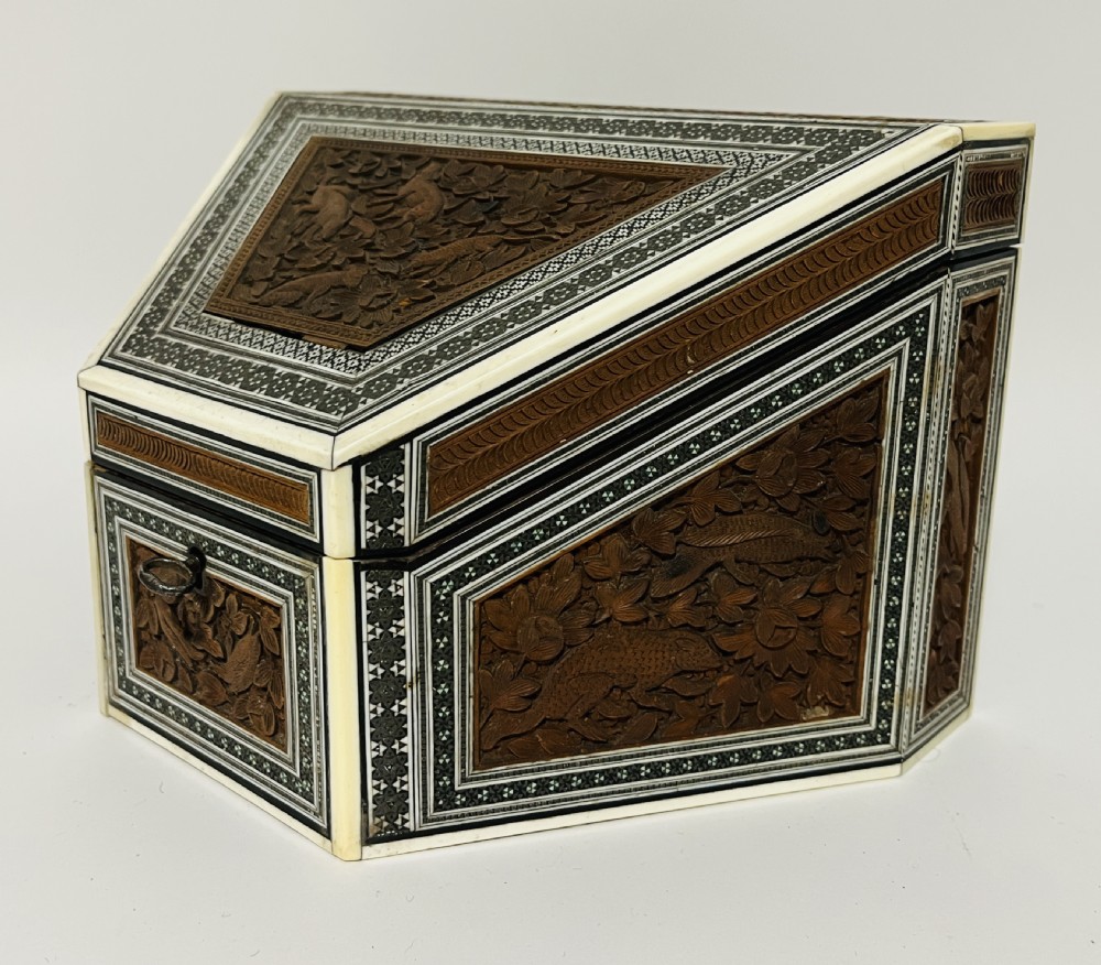A slanted Anglo-Indian stationery box crafted from carved dark wood featuring intricate geometric bone inlay borders and relief floral panels. View V