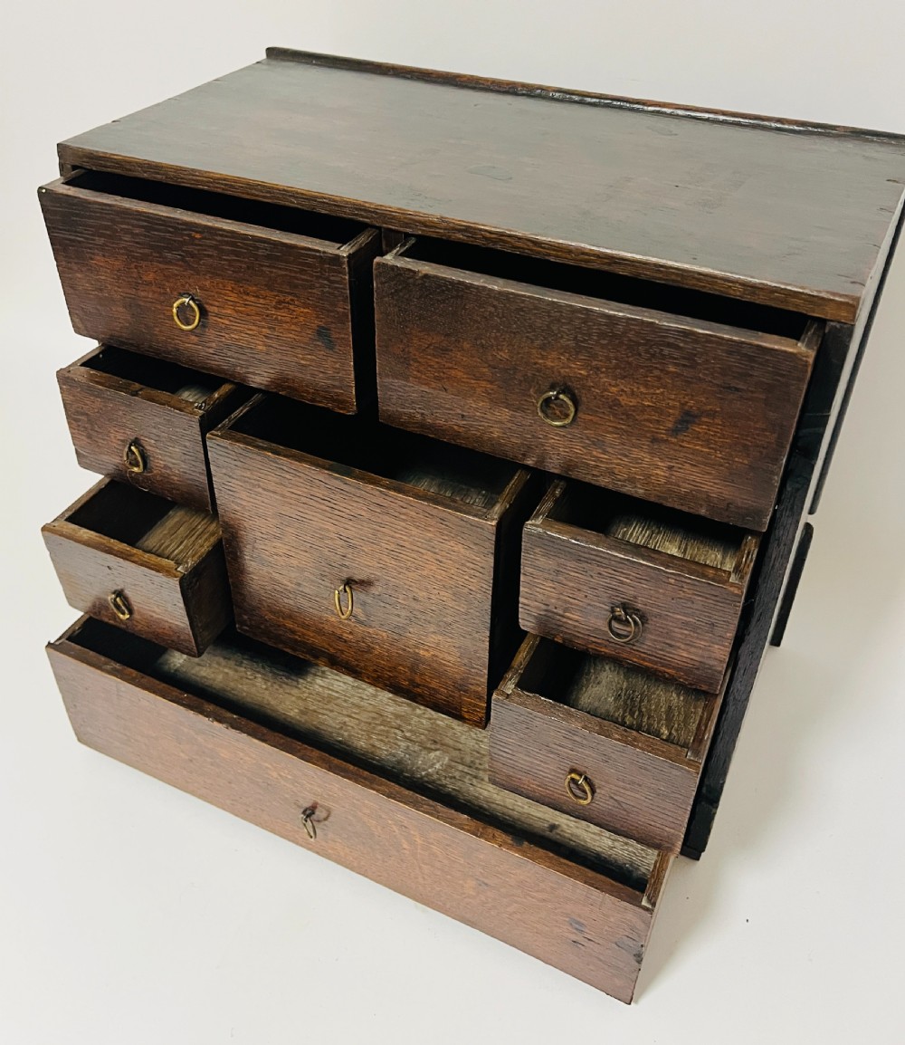 An 18th-century dark oak spice cabinet featuring multiple small drawers surrounding a central drawer, fitted with brass ring pulls. View II