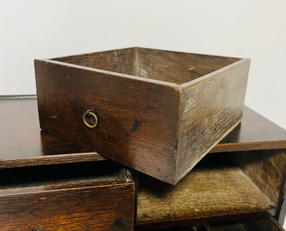 An 18th-century dark oak spice cabinet featuring multiple small drawers surrounding a central drawer, fitted with brass ring pulls. View III