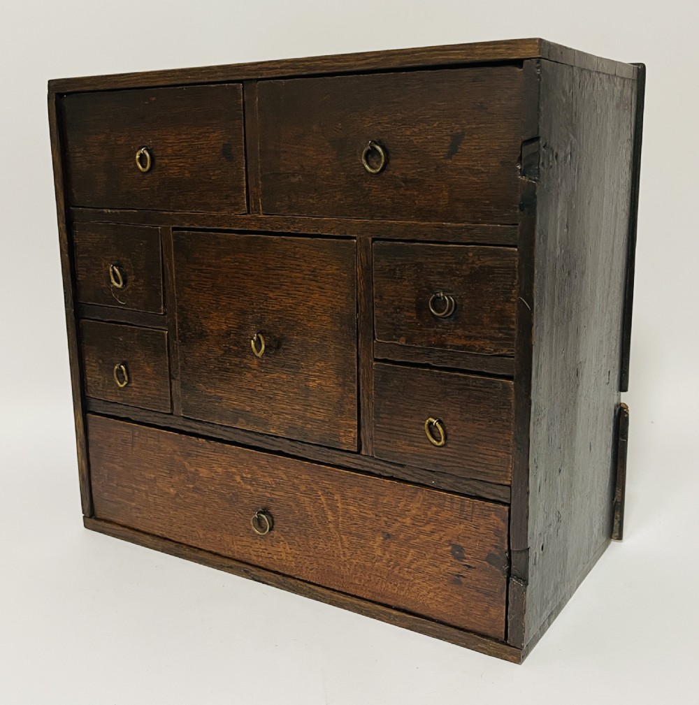 An 18th-century dark oak spice cabinet featuring multiple small drawers surrounding a central drawer, fitted with brass ring pulls. View V