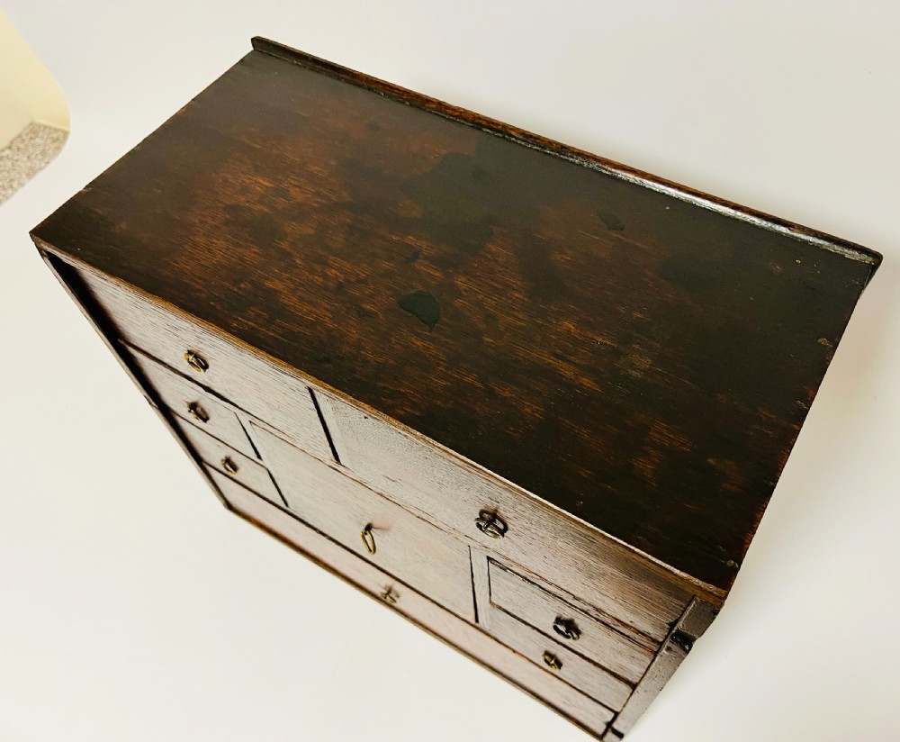 An 18th-century dark oak spice cabinet featuring multiple small drawers surrounding a central drawer, fitted with brass ring pulls. View XI