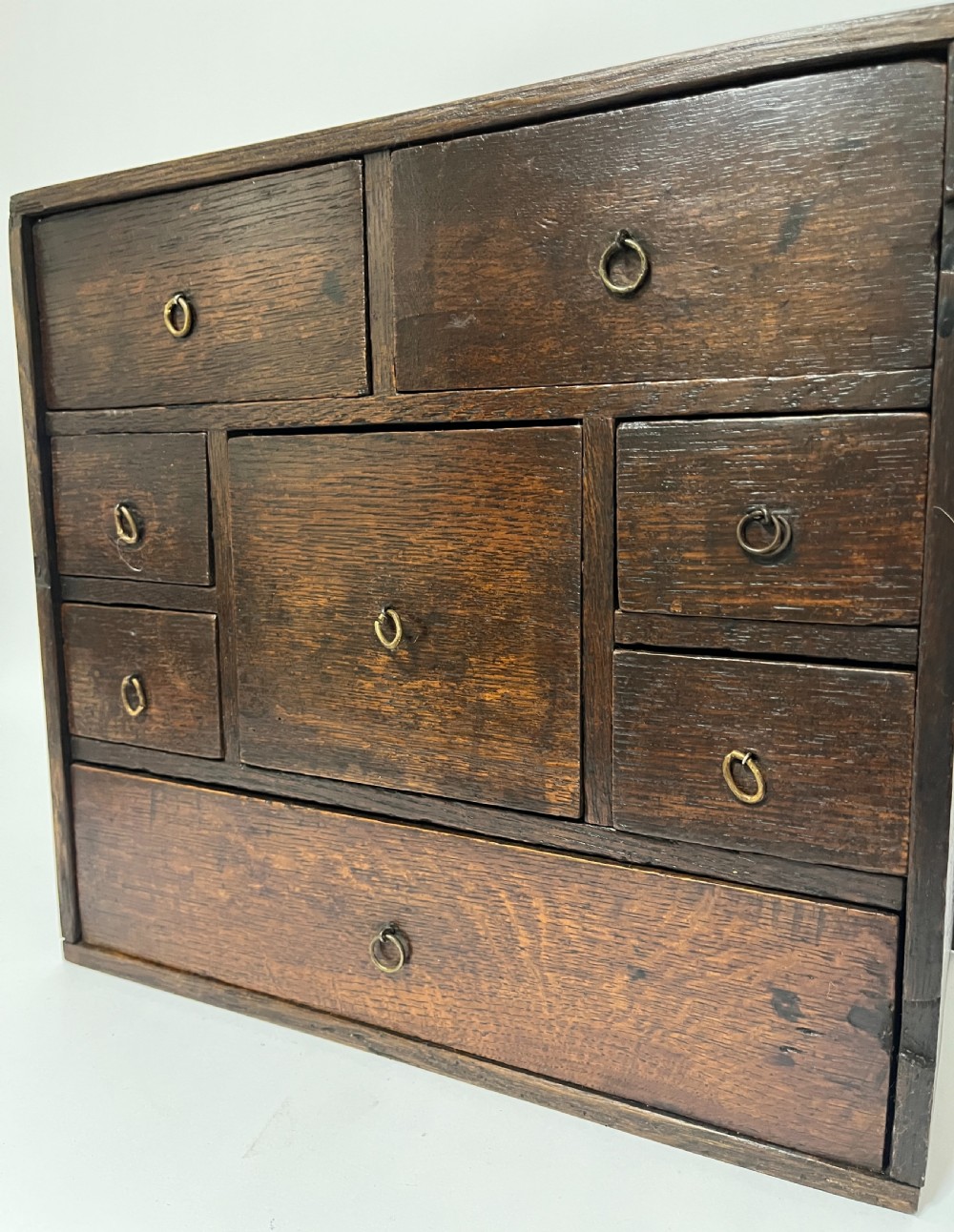 An 18th-century dark oak spice cabinet featuring multiple small drawers surrounding a central drawer, fitted with brass ring pulls. View XII