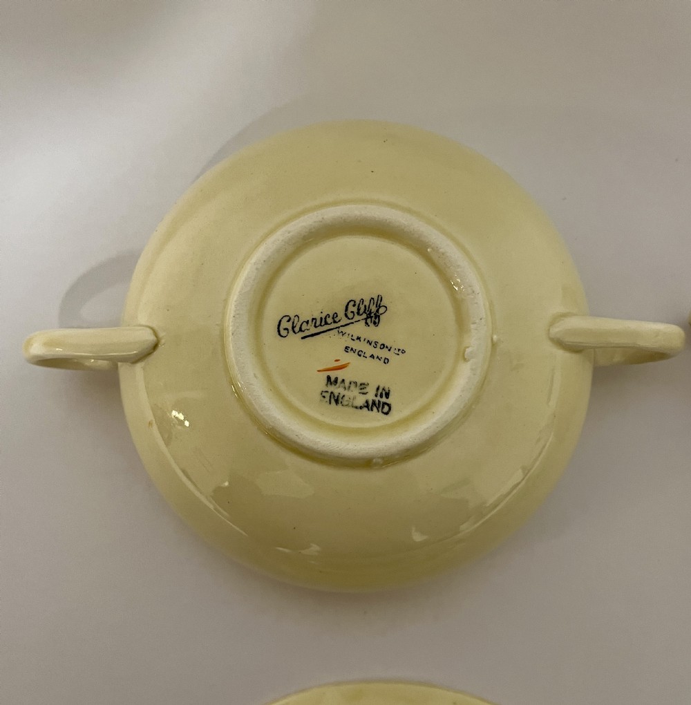 A pair of cream glazed earthenware soup coupes with twin handles and matching saucers decorated with ochre yellow, brown, and orange horizontal bands. View VIII